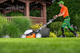 Gartenpflege: Mann beim Rasen mähen